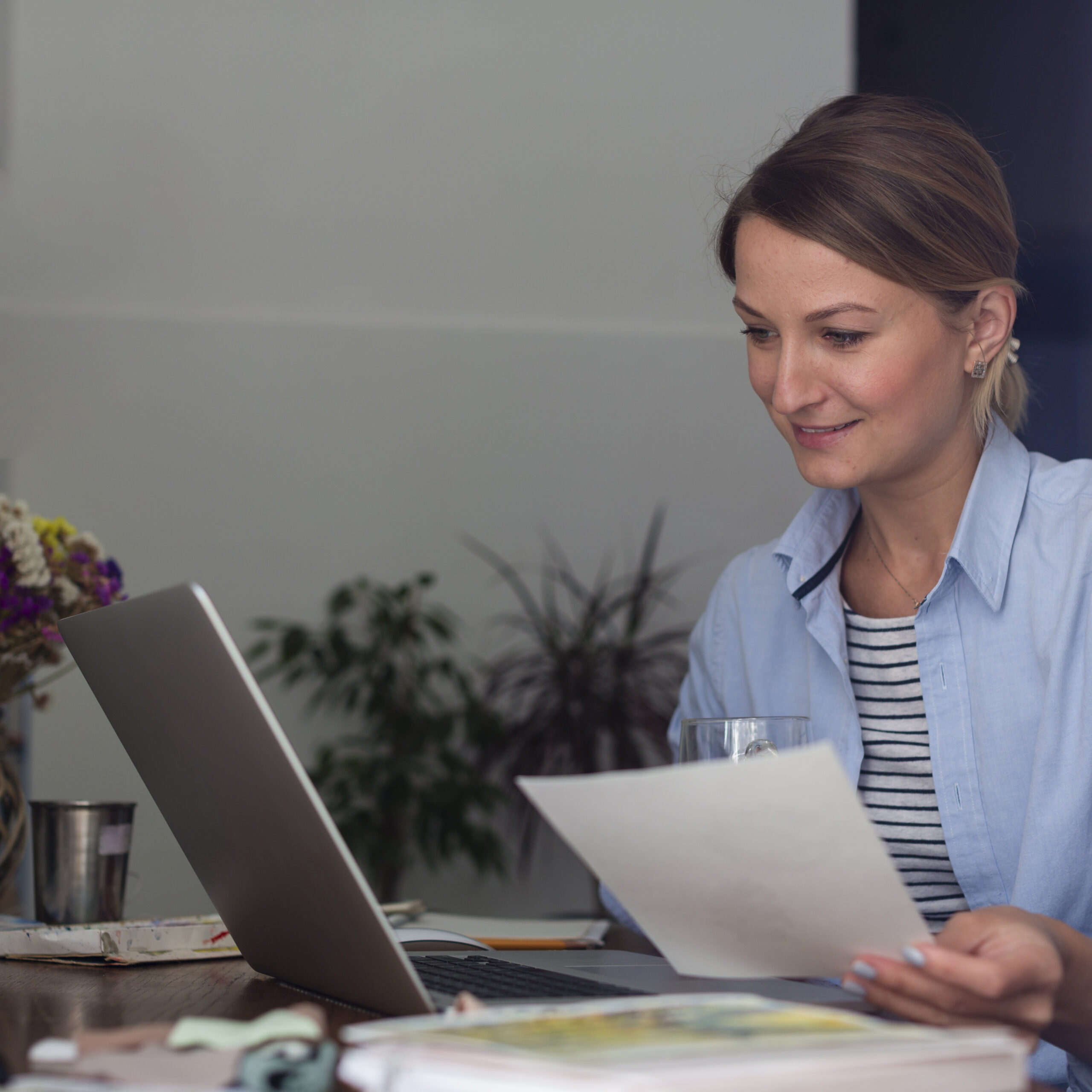 mujer-sosteniendo-papel-y-mirando-portatil